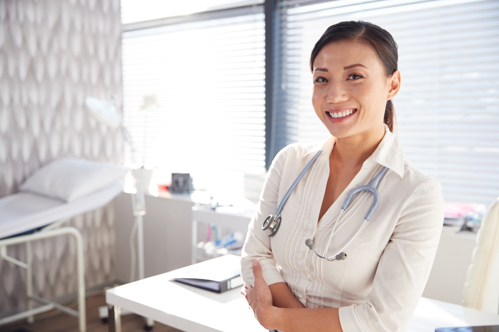 Médica sorrindo em consultório.